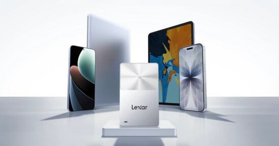 A silver Lexar external solid-state drive is displayed in front of a smartphone, a tablet, and a laptop, all positioned on a white surface with a minimalist background.