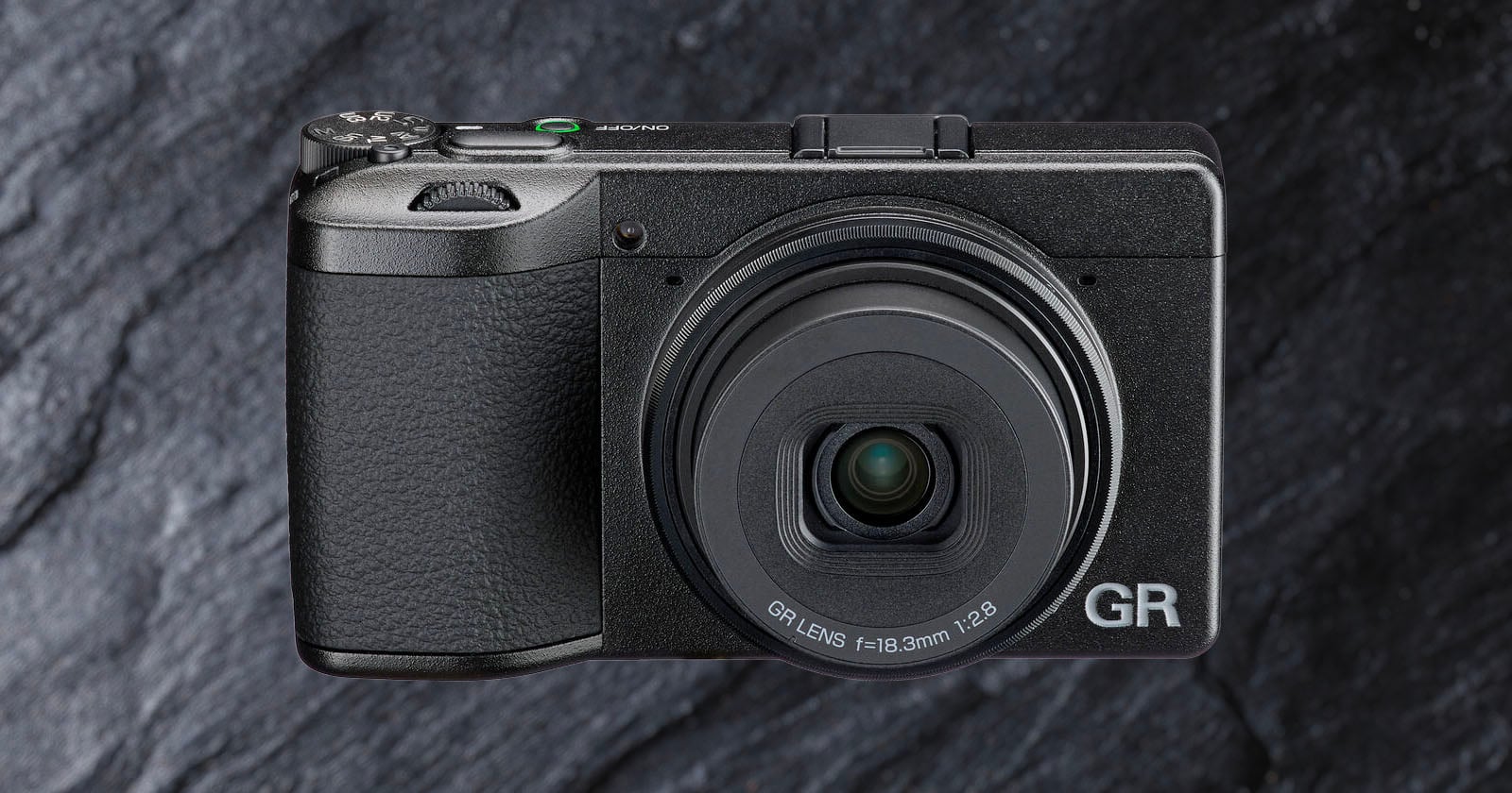 A compact black digital camera with a textured grip and a prominent lens, labeled "GR," is shown against a dark, stone-textured background.