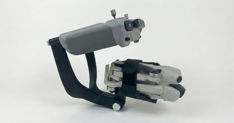 Un dron compacto está sujeto de forma segura mediante correas a un controlador negro y gris con un fondo blanco sólido.