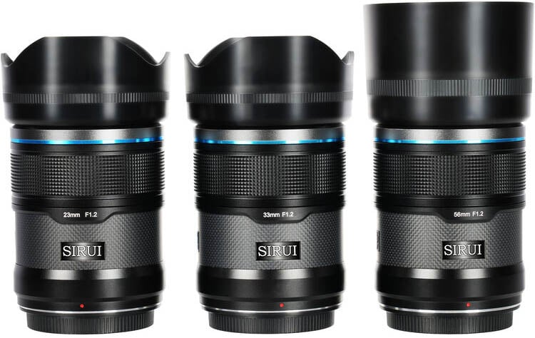 Three Sirui camera lenses are shown upright side by side. They are labeled 23mm F1.2, 33mm F1.2, and 56mm F1.2. The 56mm lens has a longer lens hood than the others. All lenses are black with blue accents.