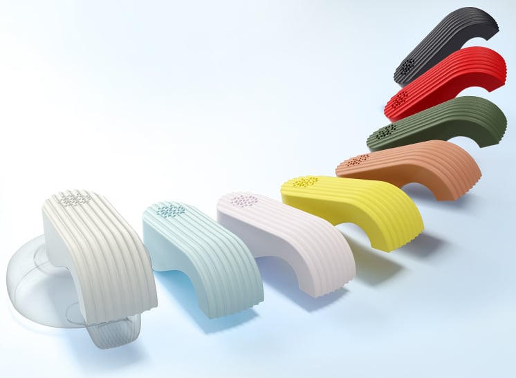 Nueve objetos curvos modernos en diferentes colores están dispuestos en diagonal sobre un fondo claro, cada uno con una parte superior texturizada y lados estriados. El primer objeto de la izquierda es parcialmente transparente y tiene una cúpula transparente.