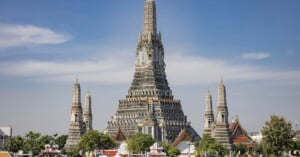 A large building with many towers with Wat Arun in the background.