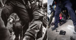 A man wearing a gas mask crouches on the ground amid armed police officers in tactical gear; a camera lies on the pavement nearby. The scene appears tense and chaotic.