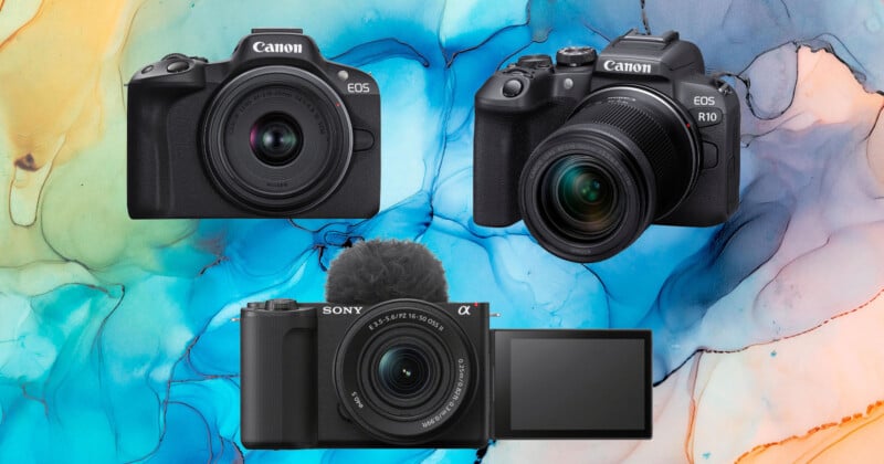 Three digital cameras (two Canon models and one Sony with a flip-out screen and microphone) are displayed against a colorful, abstract background with blue, yellow, and pink marbled patterns.