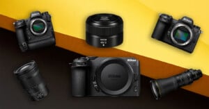 Several Nikon cameras and lenses are arranged on a yellow and orange background, including camera bodies and close-up views of various interchangeable lenses.