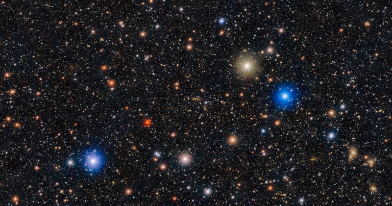 Las estrellas y galaxias densas en el espacio profundo están salpicadas de varios puntos de luz azules, blancos, amarillos y rojos brillantes sobre un fondo oscuro.