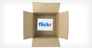 Open cardboard box with a square paper inside displaying the "flickr" logo in blue and pink letters, viewed from above against a white background.