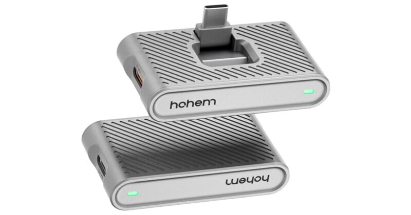 Dos dispositivos electrónicos compactos rectangulares plateados con superficies texturizadas y conectores USB-C, apilados y en ángulo. Los dispositivos tienen una luz indicadora verde y la marca 