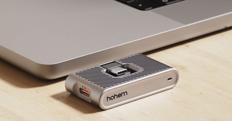 Adaptador USB-C etiquetado "alto" Conecte el portátil plateado sobre una superficie de madera. El adaptador tiene varios puertos, incluidos USB y ranuras para tarjetas de memoria.