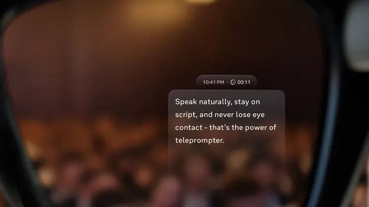 La audiencia borrosa es visible a través de una pantalla transparente, que lee el texto del teleprompter: 