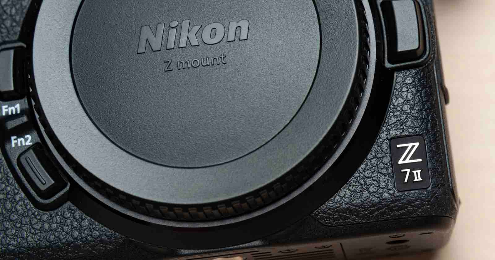 Close-up of a Nikon Z 7II mirrorless camera body, showing the textured grip, control buttons, and prominent Nikon logo on the lens mount cover.