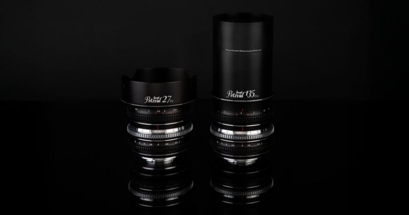 Two camera lenses, labeled "Petzval 27" and "Petzval 85," are displayed side by side on a glossy black surface with a black background. The "Petzval 85" lens has a longer barrel and lens hood.