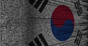 The South Korean flag is overlaid with computer code, symbolizing the intersection of technology and South Korea. The code appears in white, while the flag's colors—red, blue, and black—are clearly visible.
