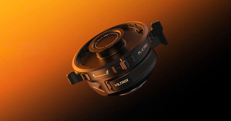 Adaptador de lentes Viiltrox, etiquetado "PLE-PRO," Se muestra sobre un vibrante fondo degradado de color naranja y negro. El adaptador cuenta con conectores metálicos y clips laterales, lo que le confiere un aspecto moderno y de alta tecnología.