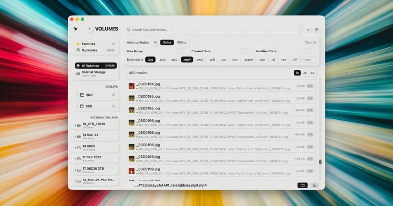 Aparece una aplicación de administración de archivos en la pantalla de la computadora que contiene una lista de archivos de imágenes y videos organizados por volumen. El fondo presenta rayas de luz colorida y borrosa que irradian hacia afuera.