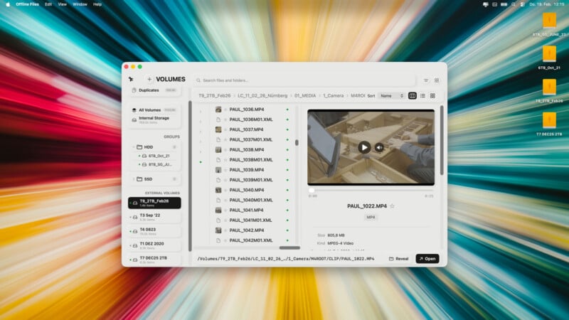 Se muestra una aplicación de administración de archivos en la pantalla de una computadora que muestra carpetas y archivos de video y muestra una vista previa de un video de las manos de una persona sobre una mesa. El fondo del escritorio presenta un patrón de explosión radial colorido. Hay cuatro carpetas naranjas en el lado derecho.