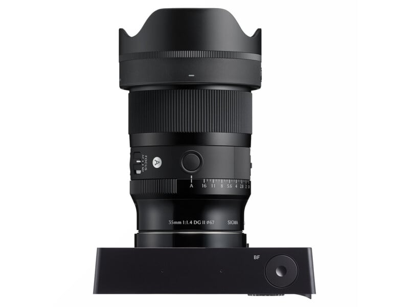 A black Sigma 35mm f/1.4 DG HSM Art camera lens stands vertically on a Sigma lens dock, with visible focus and aperture rings, switches, and lens hood attached.