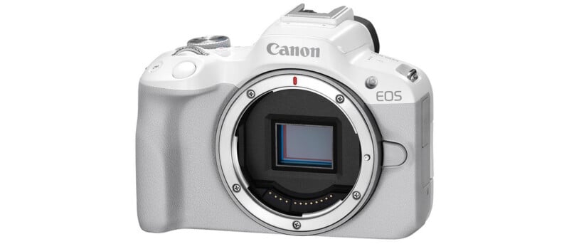 Cuerpo de cámara digital sin espejo Canon EOS blanco sin lente instalada, que muestra el sensor de imagen y los controles de la cámara sobre un fondo de color sólido.