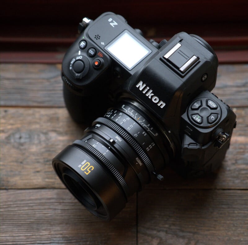 A Nikon Z series mirrorless camera with a 50mm lens attached, resting on a wooden surface.