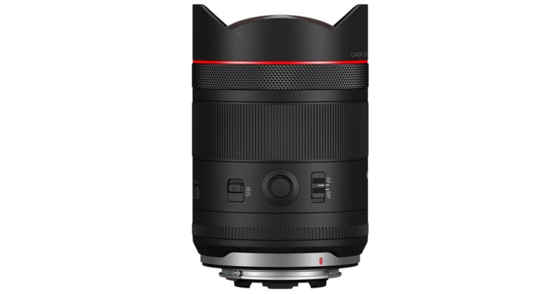 A black Canon camera lens with a red ring near the top, various switches and buttons on the side, and a silver mounting ring at the base, shown against a white background.