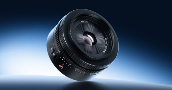 A black camera lens with white and red markings is shown floating against a blue gradient background, highlighting the glass elements and focus ring.