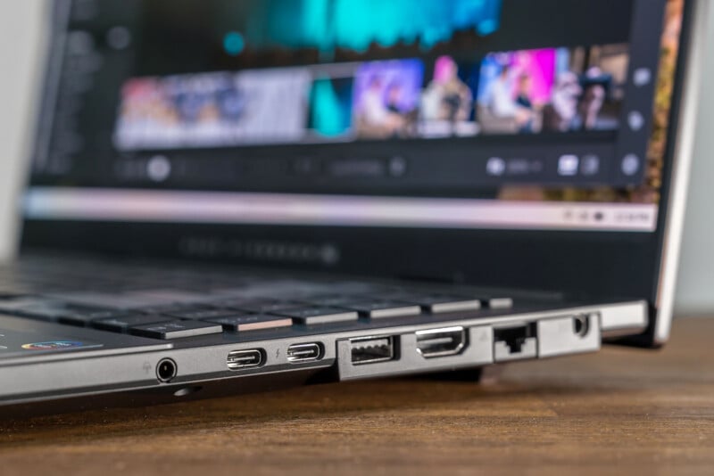 A close-up side view of a laptop showing various ports, including USB-C, HDMI, Ethernet, and USB-A, with the screen displaying a blurred multimedia interface in the background.