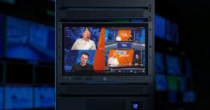A monitor in a control room displays a sports talk show with four people in separate frames discussing, with the show's logo "SPORT SHOW" visible on two screens. The background is filled with more monitors showing blurred images.