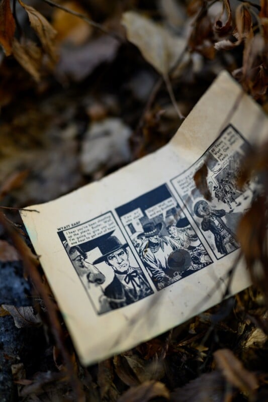 Entre las hojas secas del suelo había una tira cómica desgastada con una ilustración en blanco y negro de un personaje vestido con ropa y sombreros anticuados. Las páginas parecen viejas y ligeramente amarillentas.