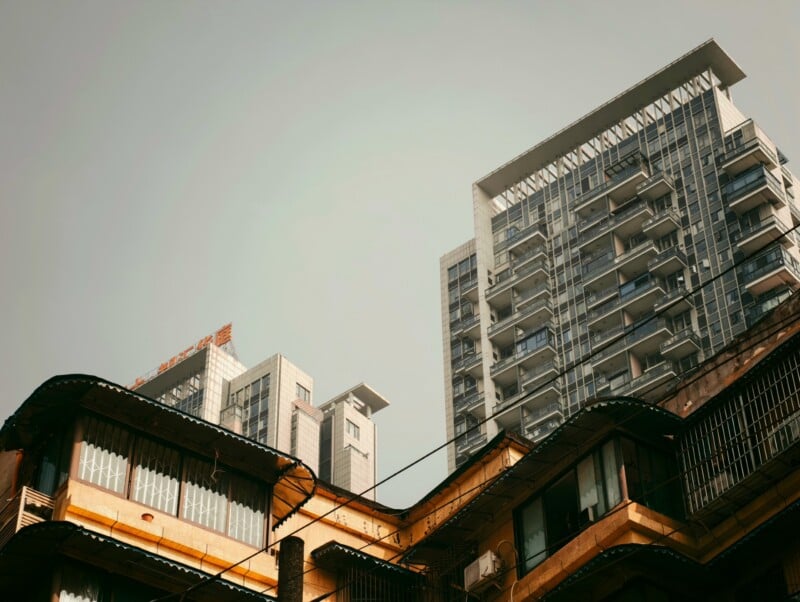 Modern high-rise buildings and older, yellow-toned apartments under a hazy sky, showcasing a contrast between contemporary and traditional architecture.