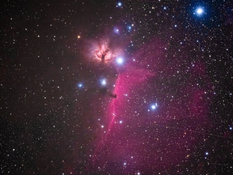 A vibrant image of deep space shows the Horsehead Nebula and Flame Nebula, with bright stars and pinkish-purple interstellar clouds set against a star-filled, dark sky.
