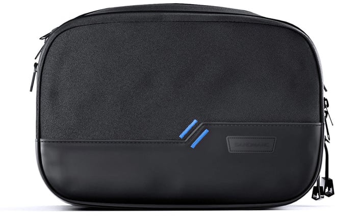 A black rectangular travel pouch with a smooth bottom section, a fabric upper section, two blue diagonal stripes, and a zippered closure on the side.