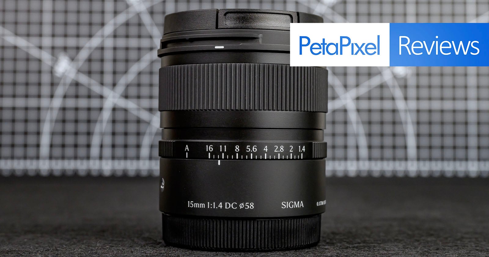 A Sigma 15mm f/1.4 camera lens stands upright on a dark surface with a geometric patterned background. A "PetaPixel Reviews" banner is overlaid in the top right corner.