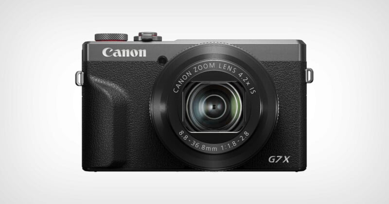 A Canon G7 X digital camera with a black body, prominent zoom lens, and Canon logo on the top left, shown facing forward against a plain light background.