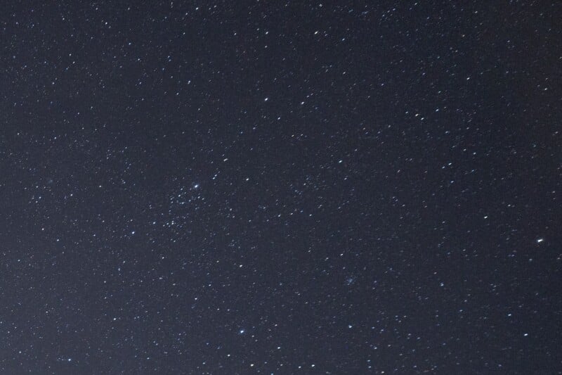 A clear night sky filled with numerous small, bright stars scattered across a dark, blue-black background. No clouds or visible landmarks, just the starry expanse.