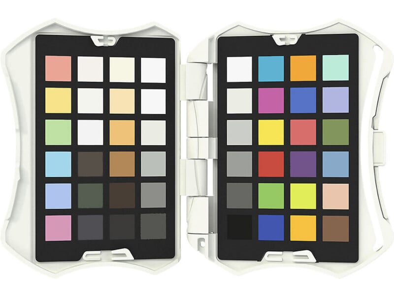 An open case displaying two color charts, each with a grid of various colored squares, used for color matching and calibration in photography or design. The case is white and hinged in the middle.