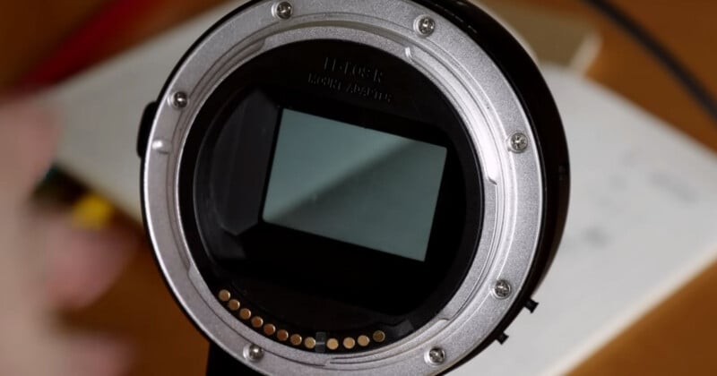 Una vista de primer plano de la montura y el sensor de la lente de la cámara, que muestra los contactos electrónicos alrededor de los bordes y un fondo borroso.