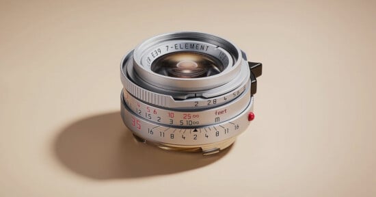 A close-up of a vintage camera lens with metallic and brass accents, engraved distance and aperture markings, and a beige background. The lens displays “7-ELEMENT” and measurement scales in red and black.