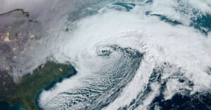 Satellite view of a large, swirling storm system with dense cloud cover over the eastern United States, stretching over the Atlantic Ocean and parts of Canada.