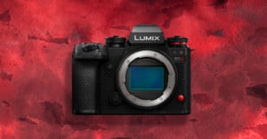 A black Panasonic Lumix S1 mirrorless camera without a lens is displayed against a textured red background.