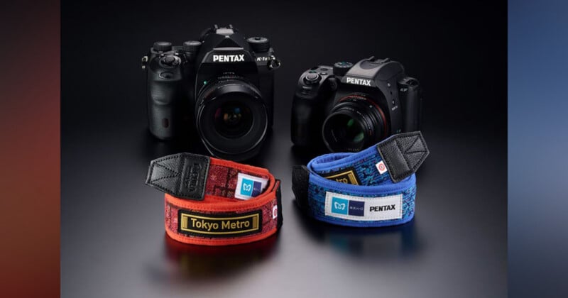 La superficie negra muestra dos cámaras Pentax, cada una con una franja colorida en la parte posterior: una roja con un parche 