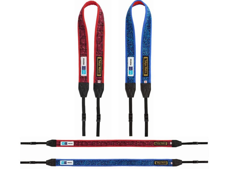 Se muestran dos correas de cámara: una roja con un patrón negro y otra azul con un patrón negro. Ambos tienen extremos negros y correas de ajuste, así como etiquetas y etiquetas adheridas cerca de la parte superior.