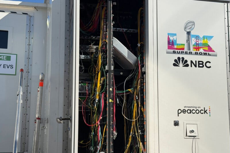 A equipment trailer with open doors reveals tangled wires and cables inside. The trailer exterior displays the Super Bowl LVI logo, NBC logo, and Peacock streaming info.