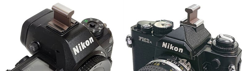 Close-up views of two Nikon cameras, each with a silver thumb rest accessory attached to the hot shoe mount on top. The cameras are shown from an angled perspective.