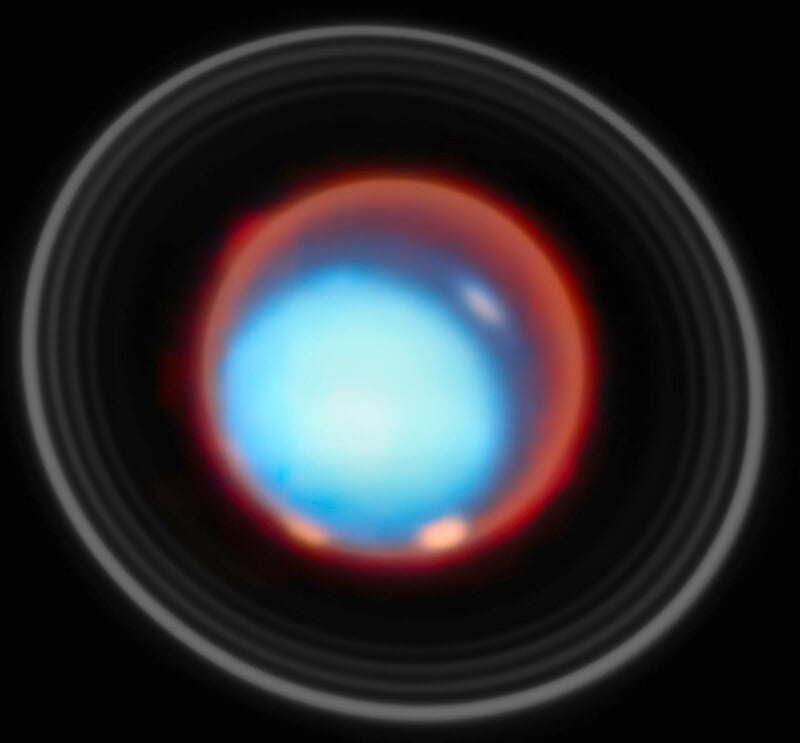 Una esfera azul brillante con un anillo exterior de color naranja rojizo y varios círculos concéntricos tenues sobre un fondo negro, creando una apariencia celestial abstracta.
