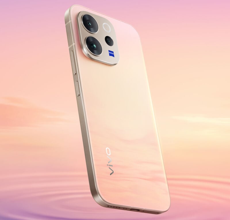 A peach-colored Vivo smartphone is shown floating above a rippled water surface, against a soft pastel sunset sky. The phone features dual rear cameras and a sleek, reflective back design.