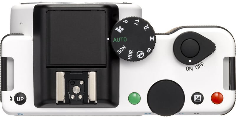 Top view of a white digital camera showing a mode dial, shutter button with an on/off switch, hot shoe mount, and various control buttons.