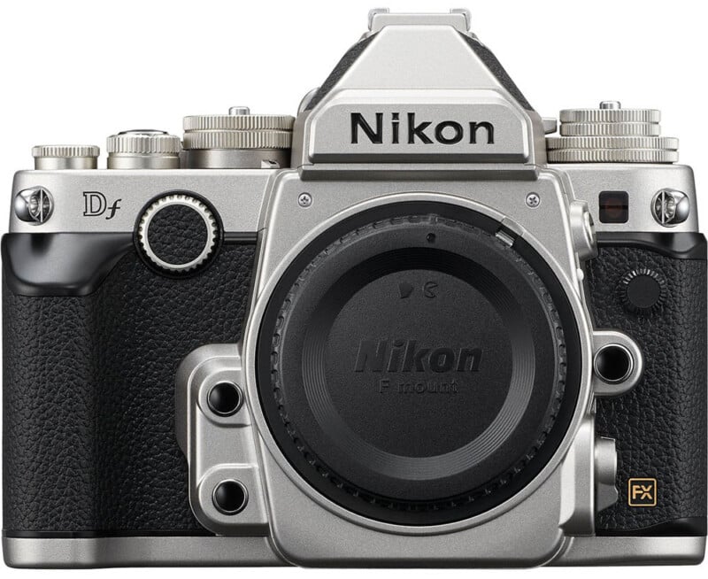 Front view of a silver and black Nikon Df digital camera body, showing its textured grip, control dials, and lens mount without a lens attached.
