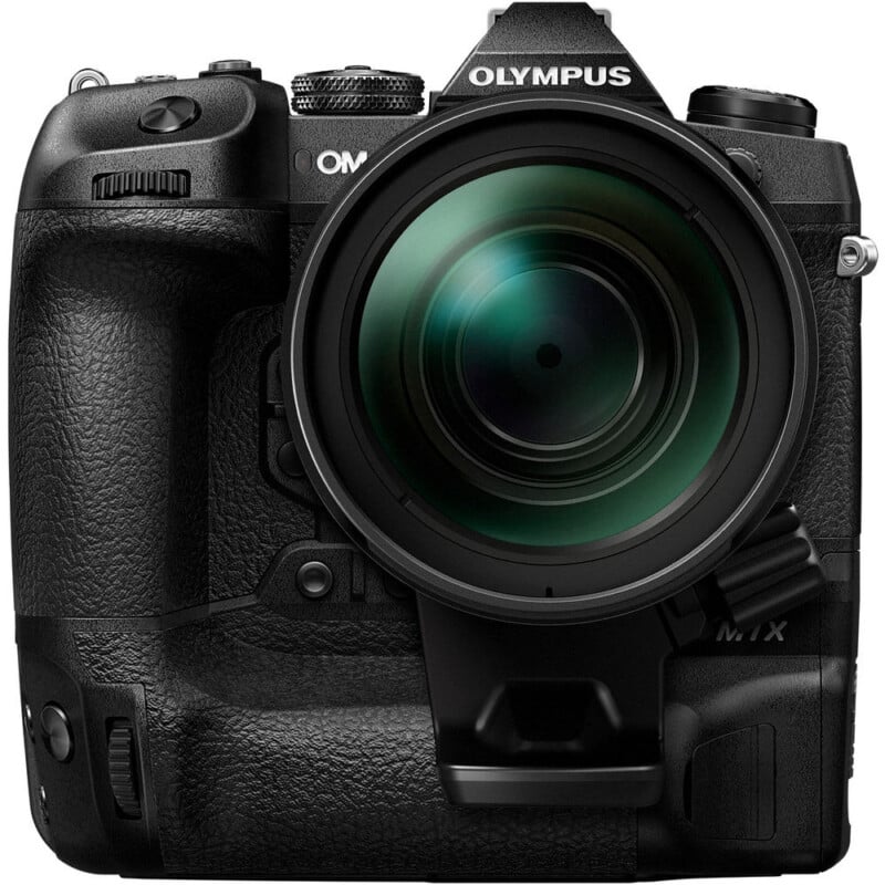 Close-up front view of a black Olympus OM-D E-M1X digital camera with a large lens attached, showing detailed controls, buttons, and textured grip on the camera body.