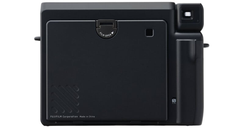 Vista trasera de una cámara instantánea de película Fuji negra, que muestra el compartimento de película cerrado, el pequeño visor cuadrado en la esquina superior derecha y el asa a la derecha. 