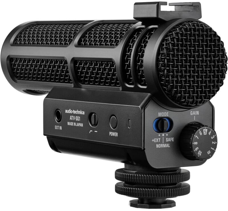Micrófono de cañón Audio-Technica ATY-SG1 negro con rejilla de malla, botones de control y perilla de ganancia, montado en el adaptador de zapata de la cámara.